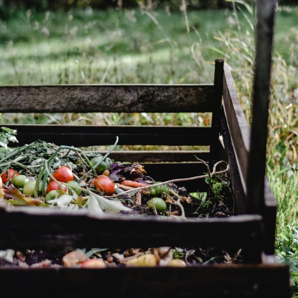 Wooden compost bin in an Estonian garden with organic waste and vegetables.